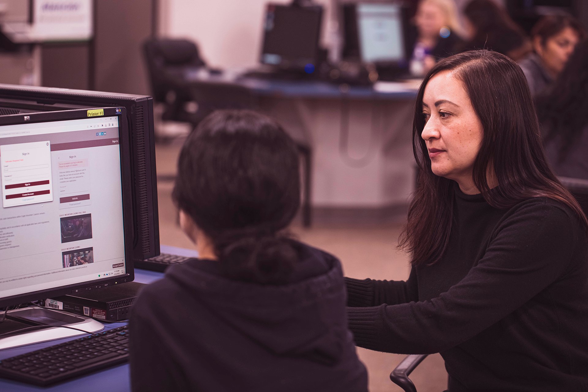 A young adult working at a computer with the assistance of a female career coach.