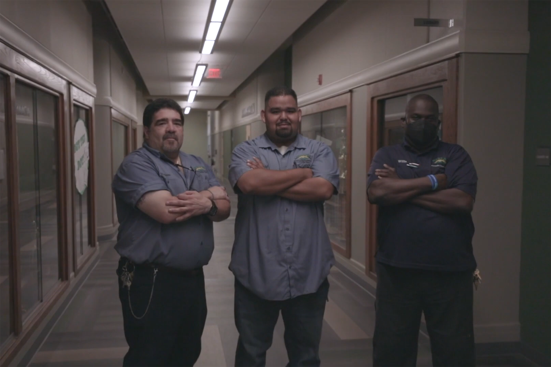 Three janitorial staff standing in the hallway of a school.