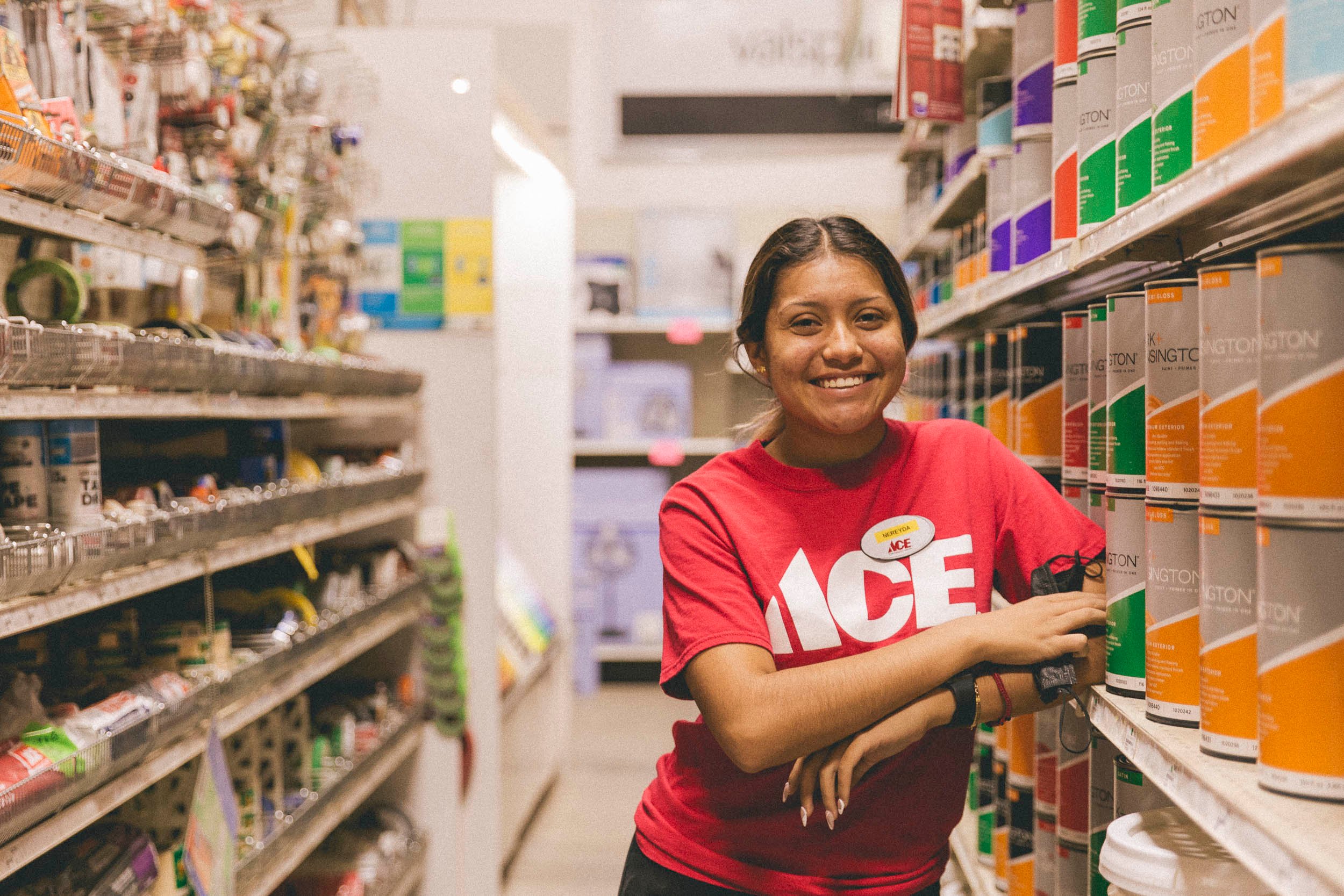 A teenage female employee standing in an aisle of a hardware store