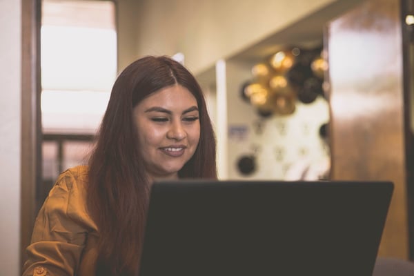 Image of a young woman using a laptop to find job leads.