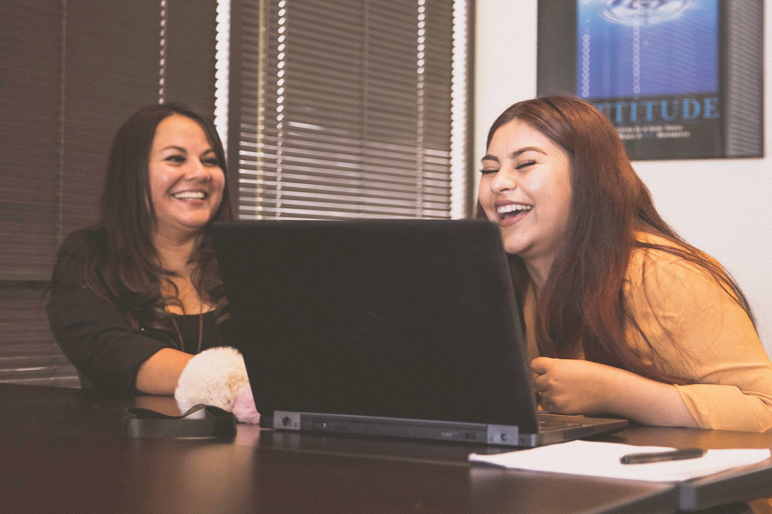 Two young women working at a desk with a laptop.