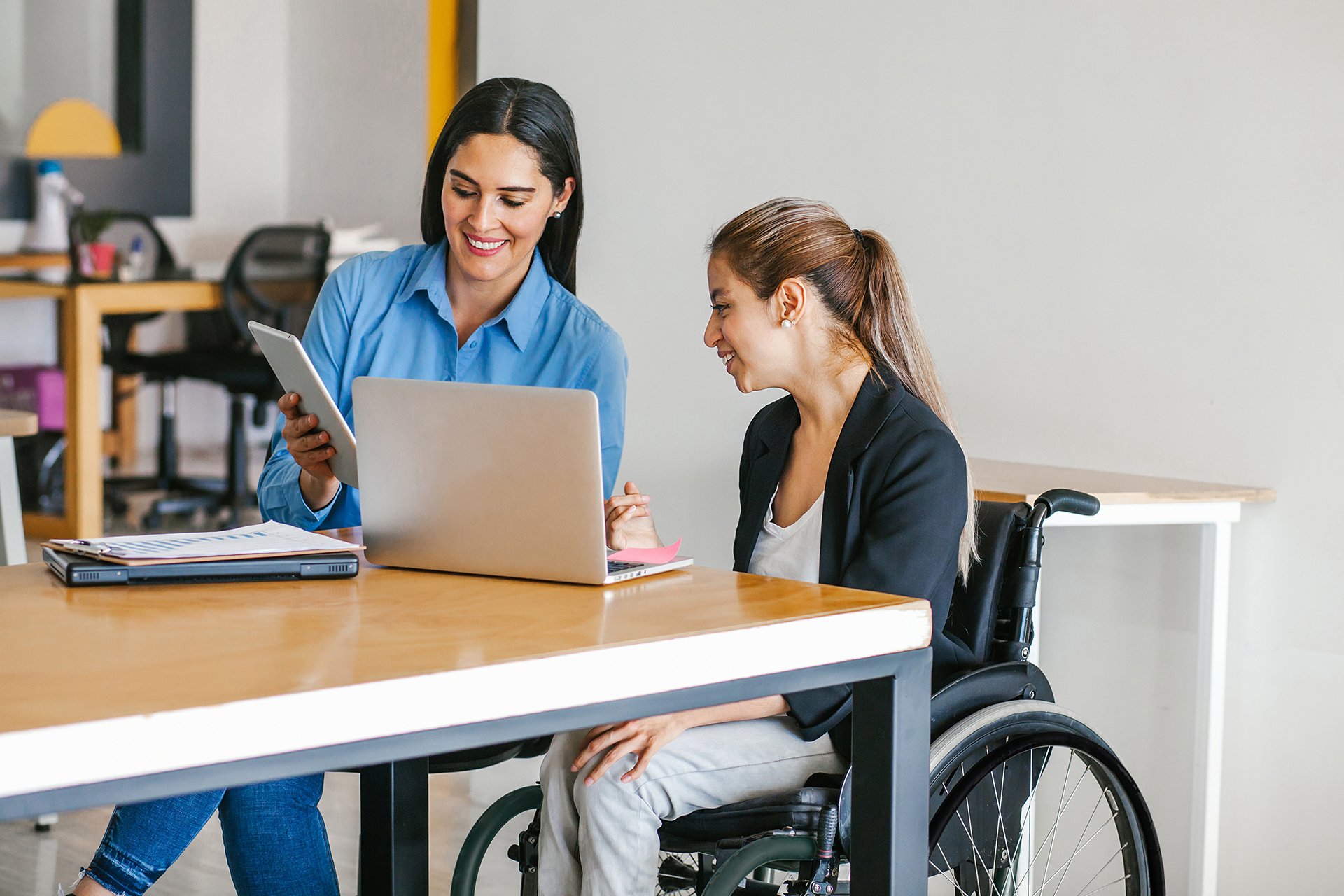 A female supervisor showing data to a woman in a wheelchair