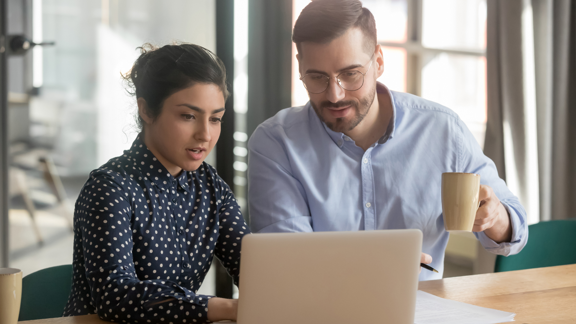 Middle aged man helping a young woman at a computer