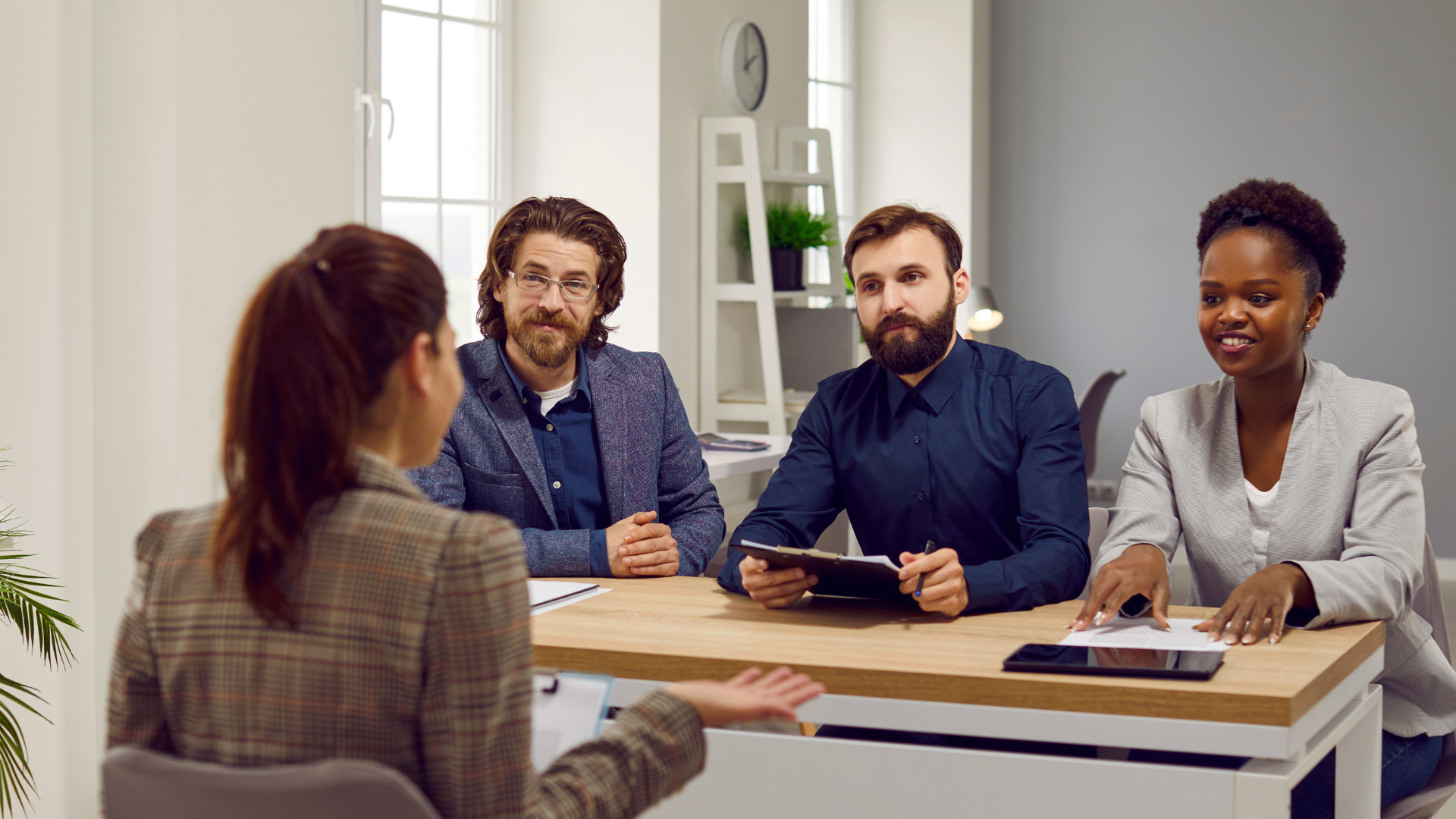 A woman participating in a panel interview with 3 people on the other side of the table.