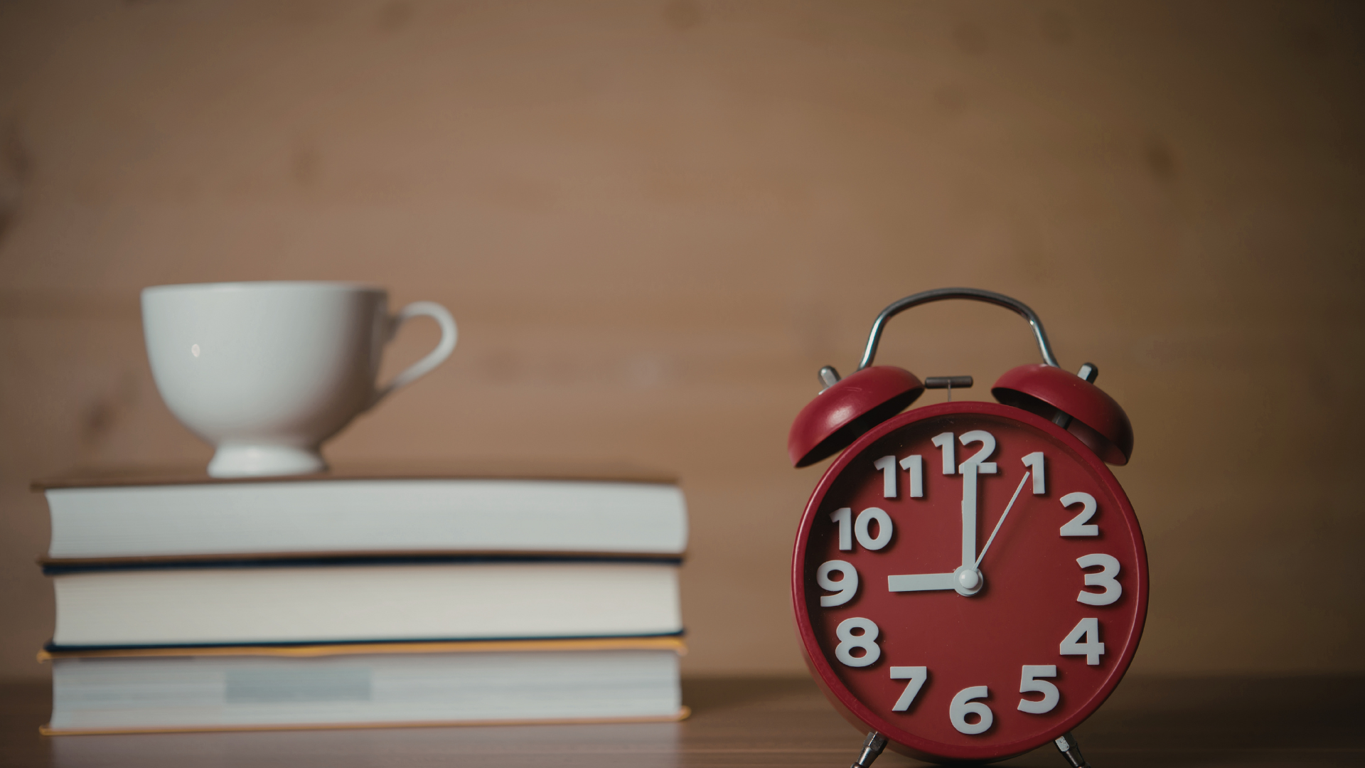 stack of books with a coffee cup and a small clock