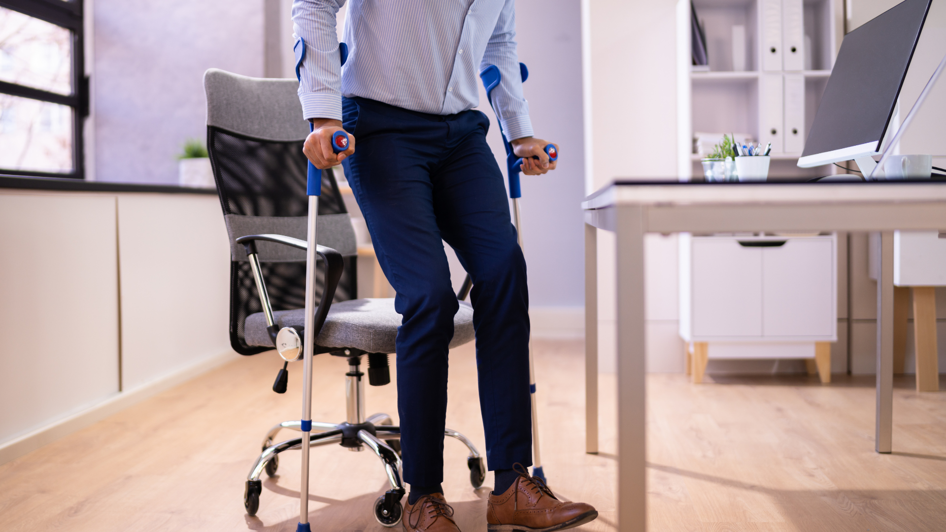 Man at a desk using a cane to stand up