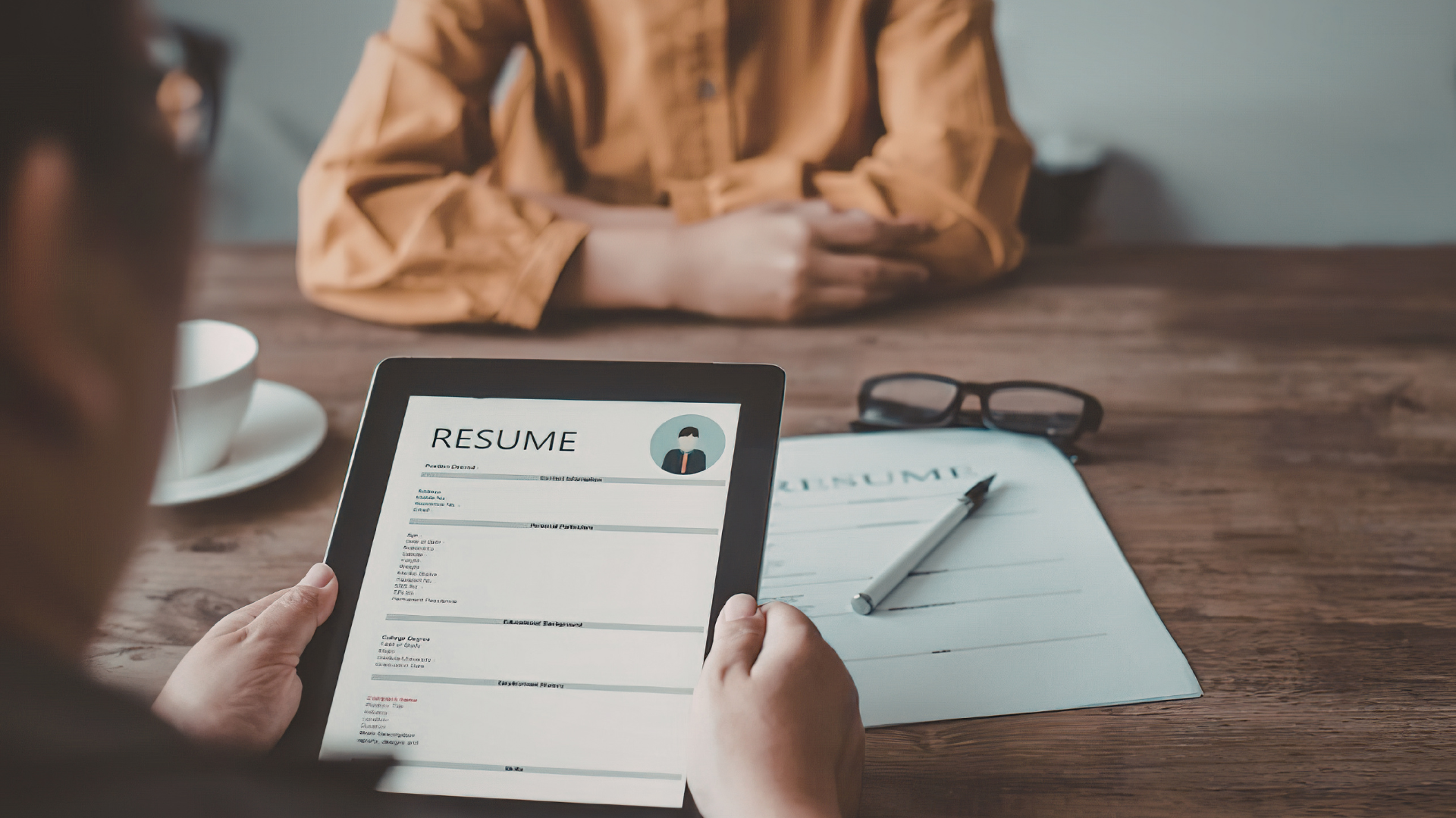 2 people in an interview with a resume showing on a tablet