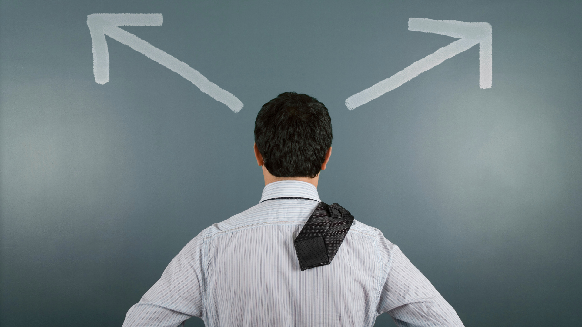 Man looking at a wall with two arrows pointing in opposite directions