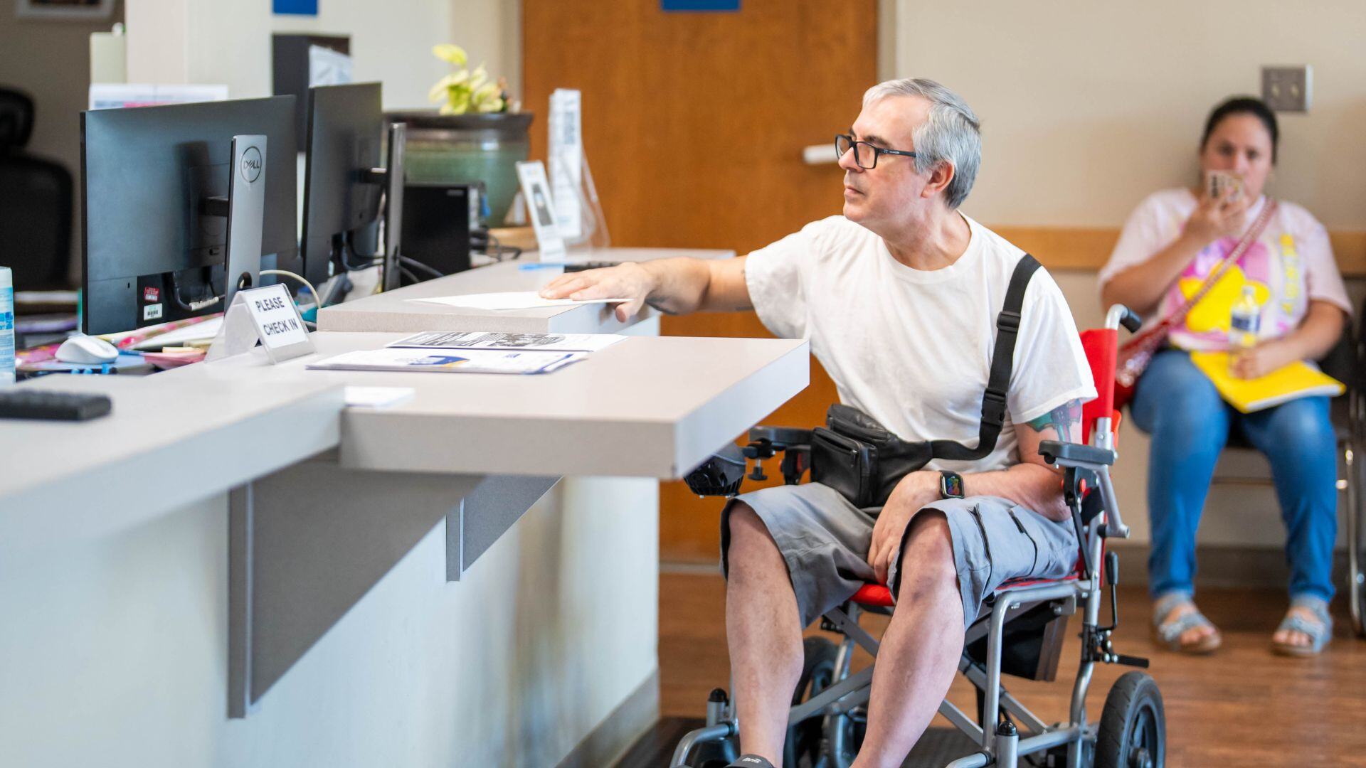man in a wheel chair at a reception desk