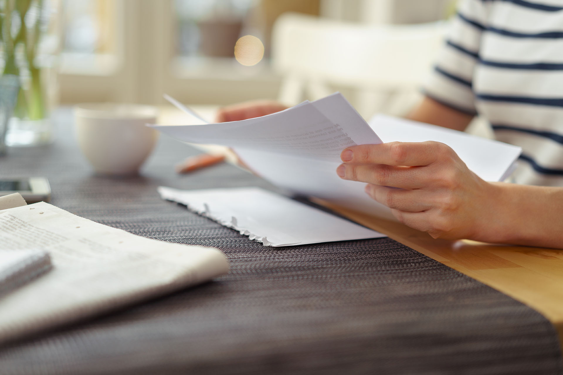 The hands of someone holding a paper resume at a desk.
